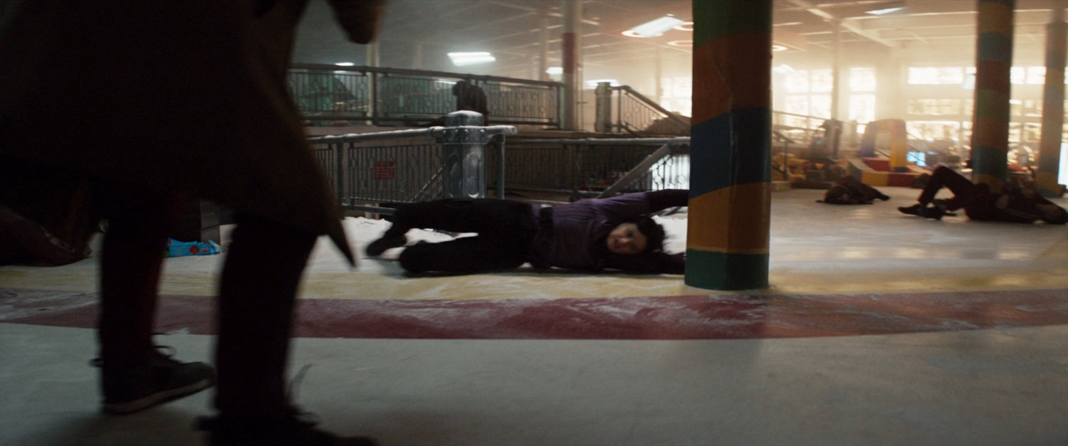 Kate swinging around a column in an abandoned toy store.