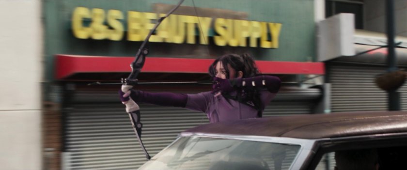 Kate fires arrows out passenger window of speeding car.