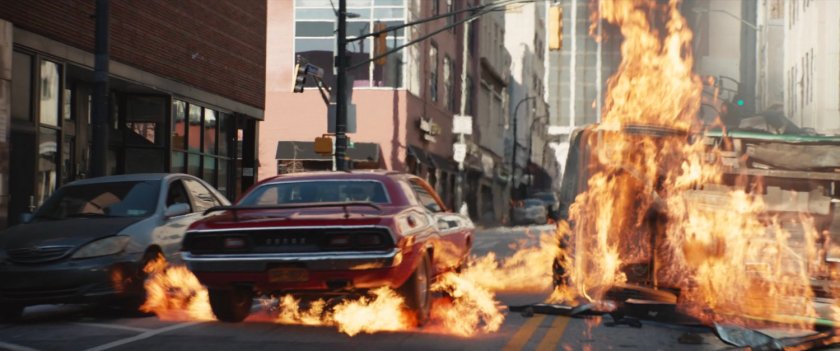 Car driving through flaming debris.