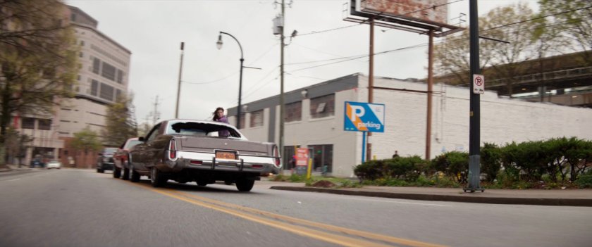 Cars racing backwards on a New York street.