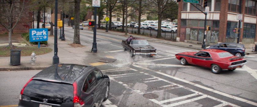 Cars race through an intersection by a Christmas tree lot.