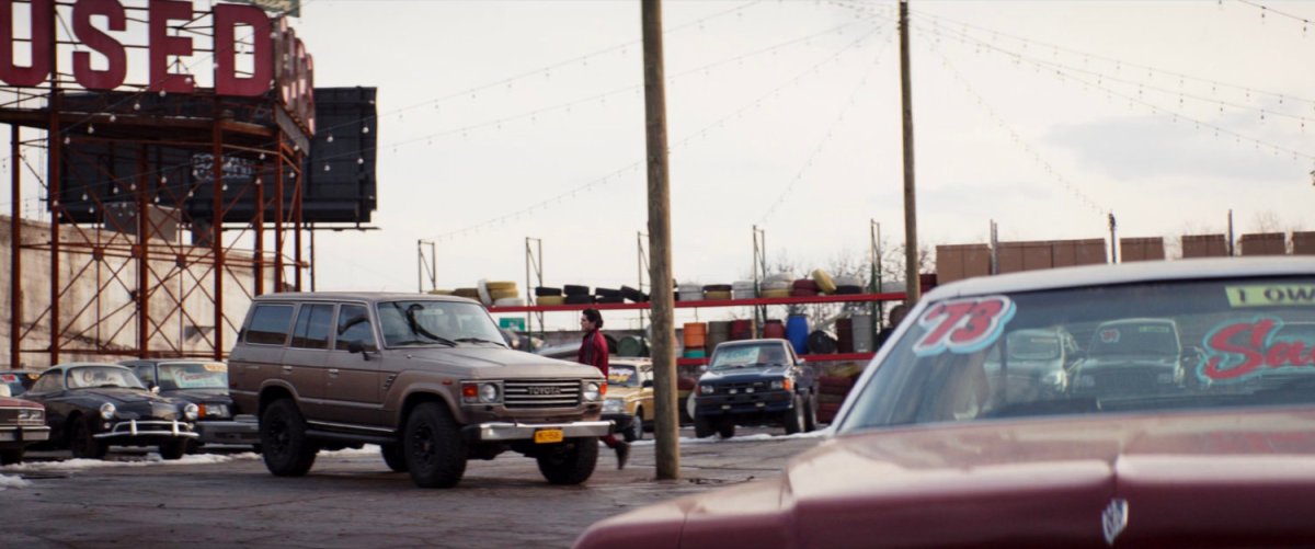 Kazi approaches a truck in the parking lot of Fat Man Used Cars.