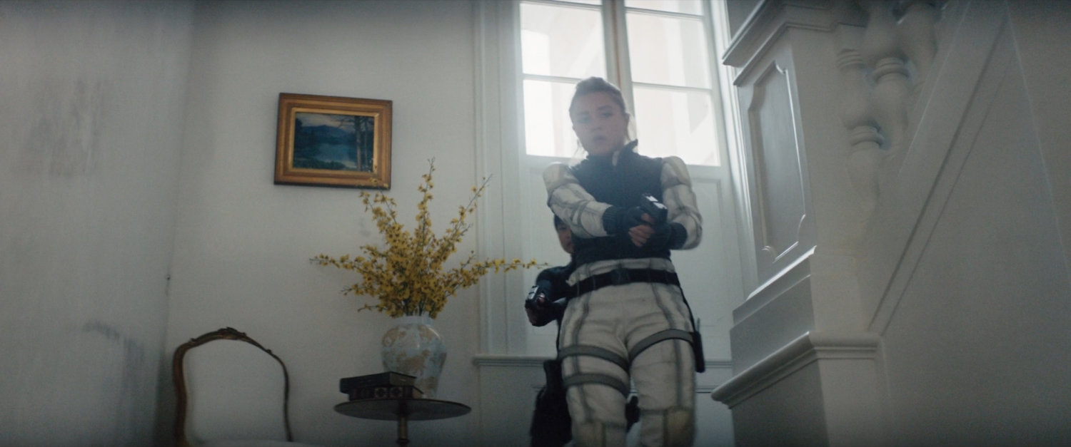 Yelena walking down stairs in Ana's mansion.