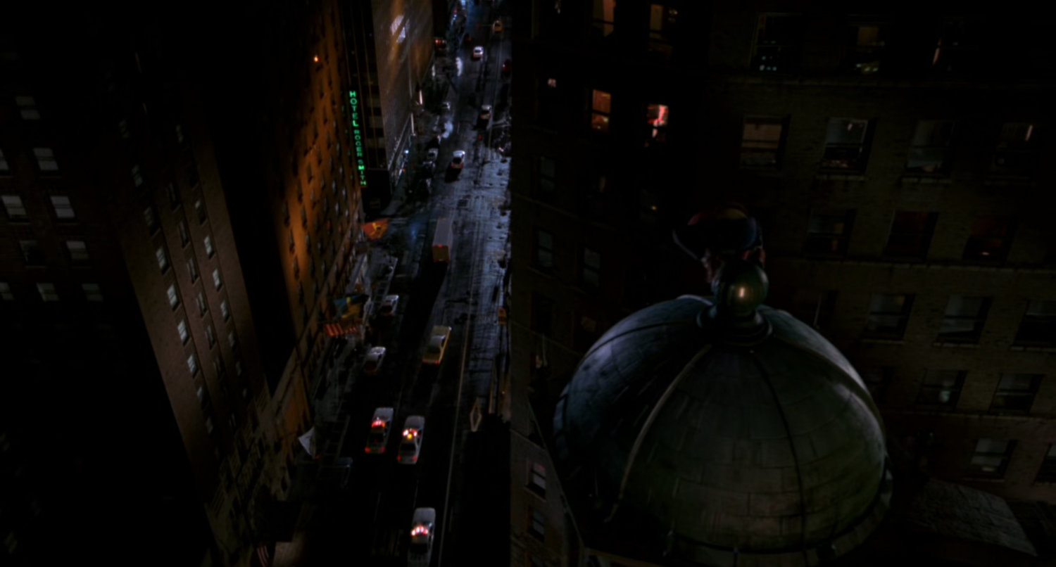 Spider-Man sitting on dome overlooking street.