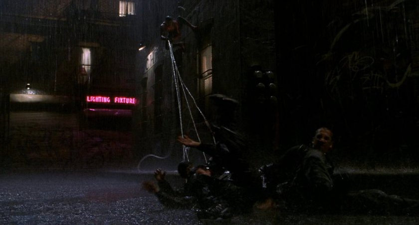 Spider-Man attacks muggers at night in a rainy alley.