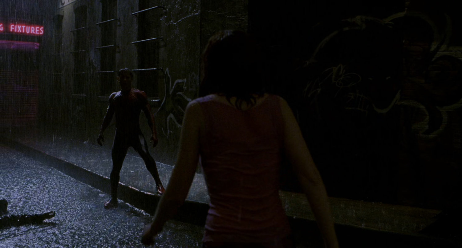 Spider-Man and Mary Jane at night in a rainy alley.