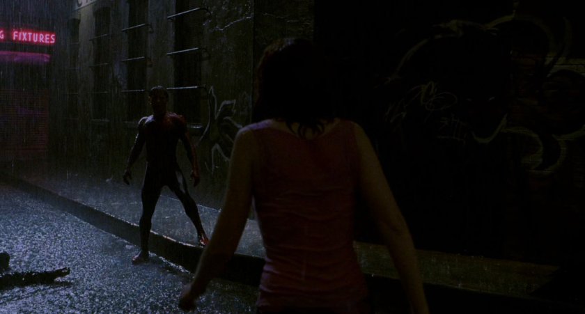 Spider-Man and Mary Jane at night in a rainy alley.