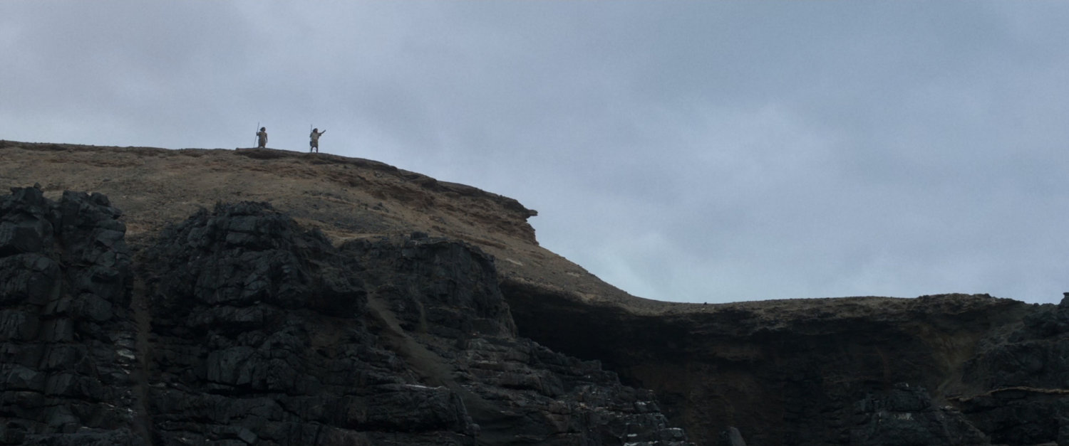 Two figures a top a hill.