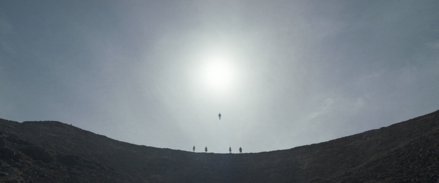 Four small figures on a ridge are joined by a fifth that hovers in the sky.
