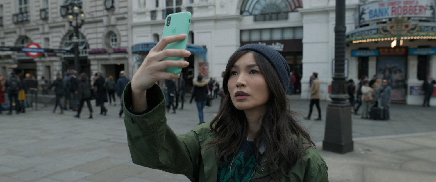 Sersi holding her phone up in Piccadilly Circus.