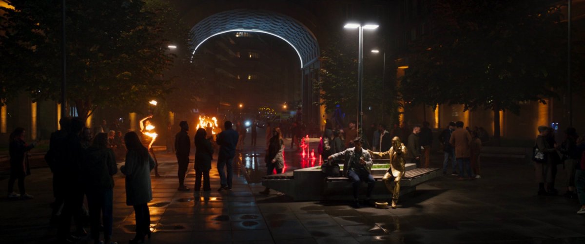 Steven sits on a bench next to the living statue in a London plaza.