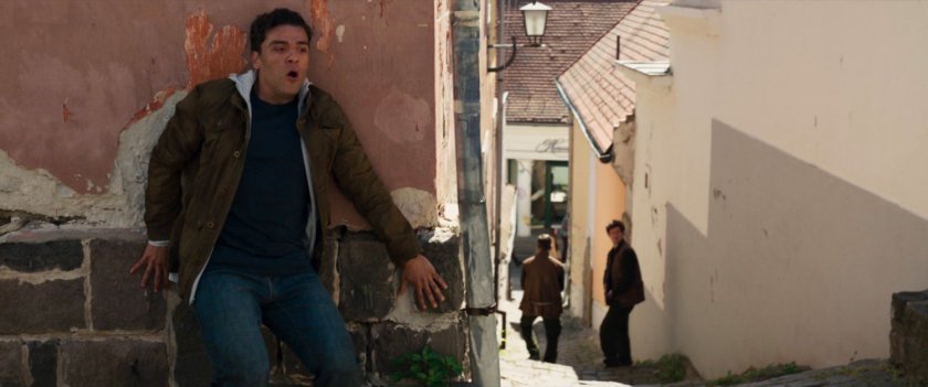 Steven hides behind a wall in a German village.