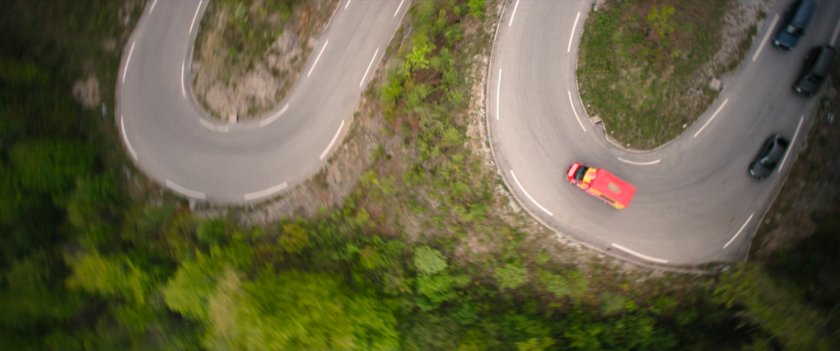 Aerial view of cupcake truck being chased down alpine road in Germany.