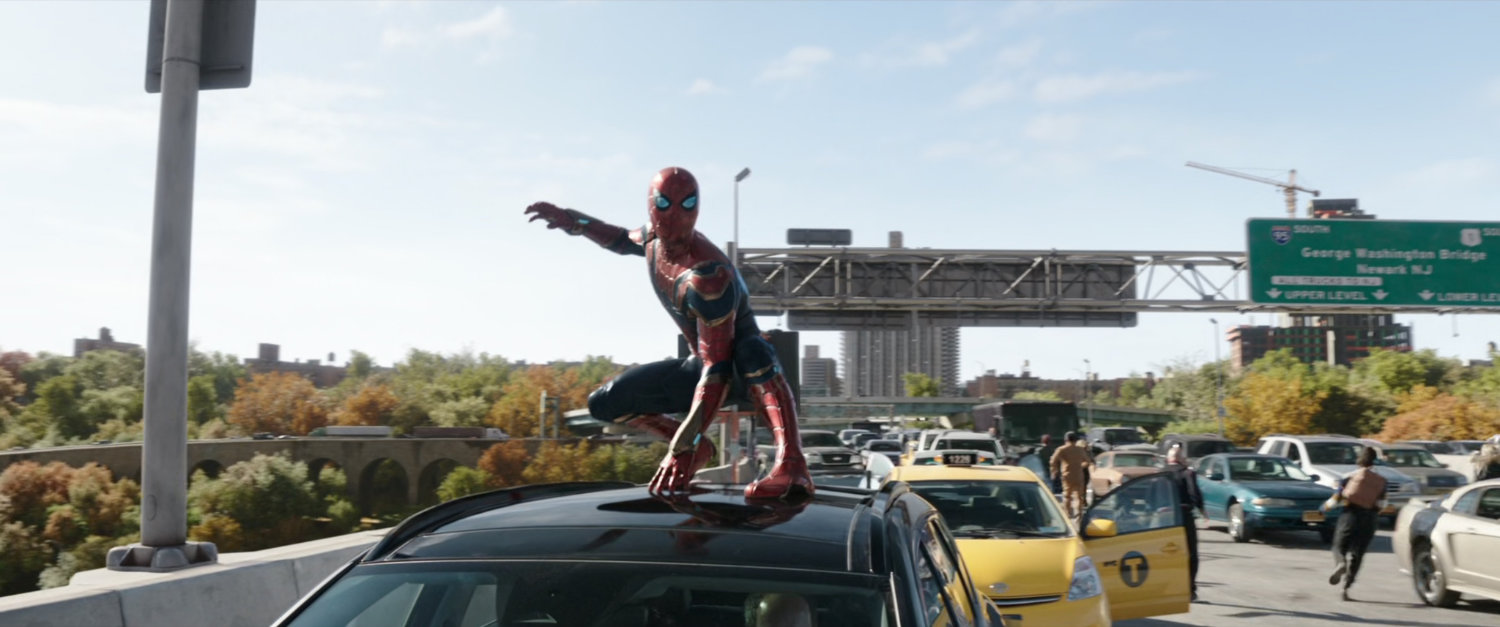 Spider-Man perches on top a car parked on a freeway bridge.