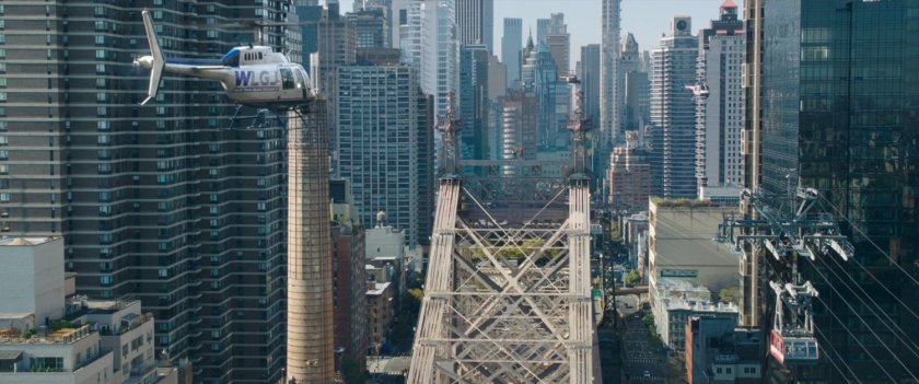 A helicopter hovers over the Queensboro Bridge, with New York in background.