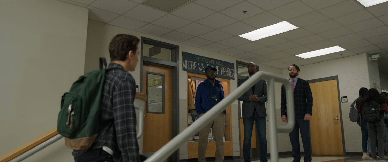 Peter Parker walking up stairs towards teachers inside Midtown High.