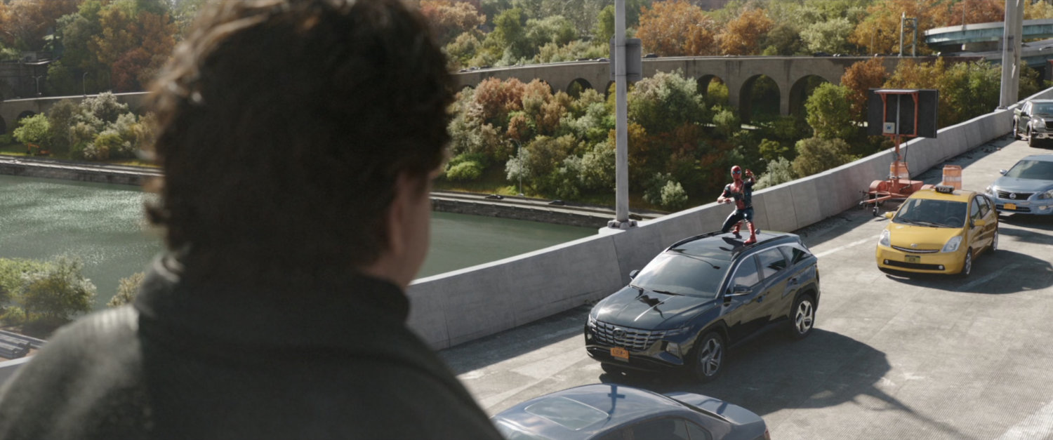 Doctor Octopus towering above Spider-Man who is standing on a car on the Alexander Hamilton Bridge.