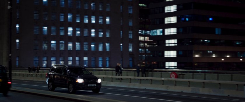 Nighttime shot of car driving across bridge in London.