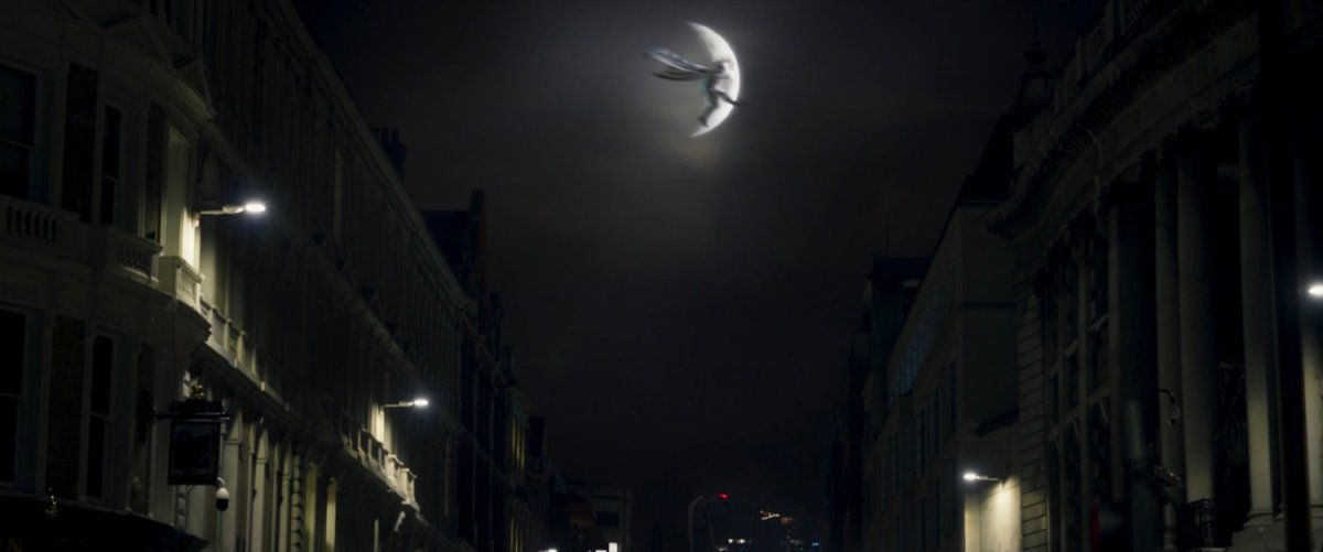 Moon Knight jumping between two London buildings and silhouetted by the moon.