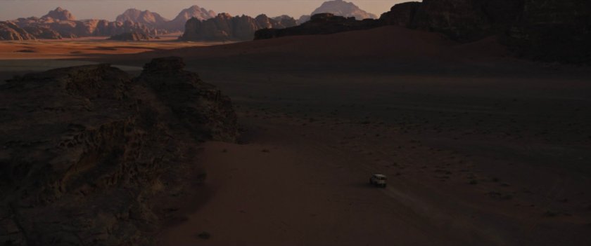 A lone car on a road in the Egyptian desert at twilight.
