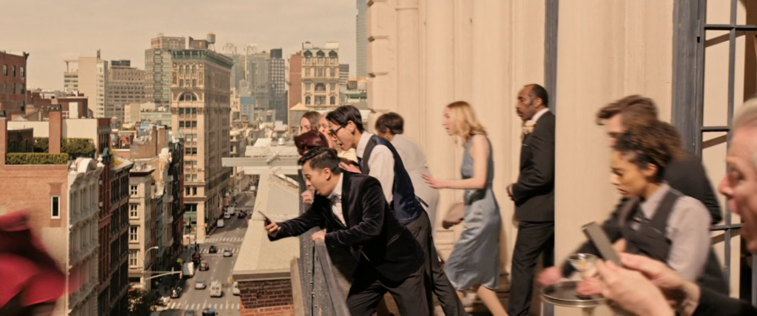 Crowd on balcony looks down on Soho street in New York City.