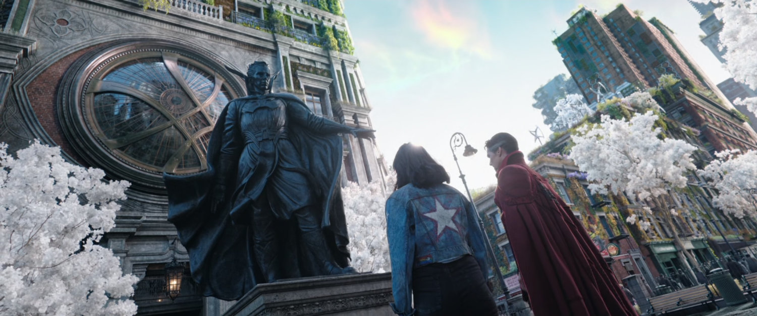 America and Dr Strange look at Dr Strange statue in alternate New York city.