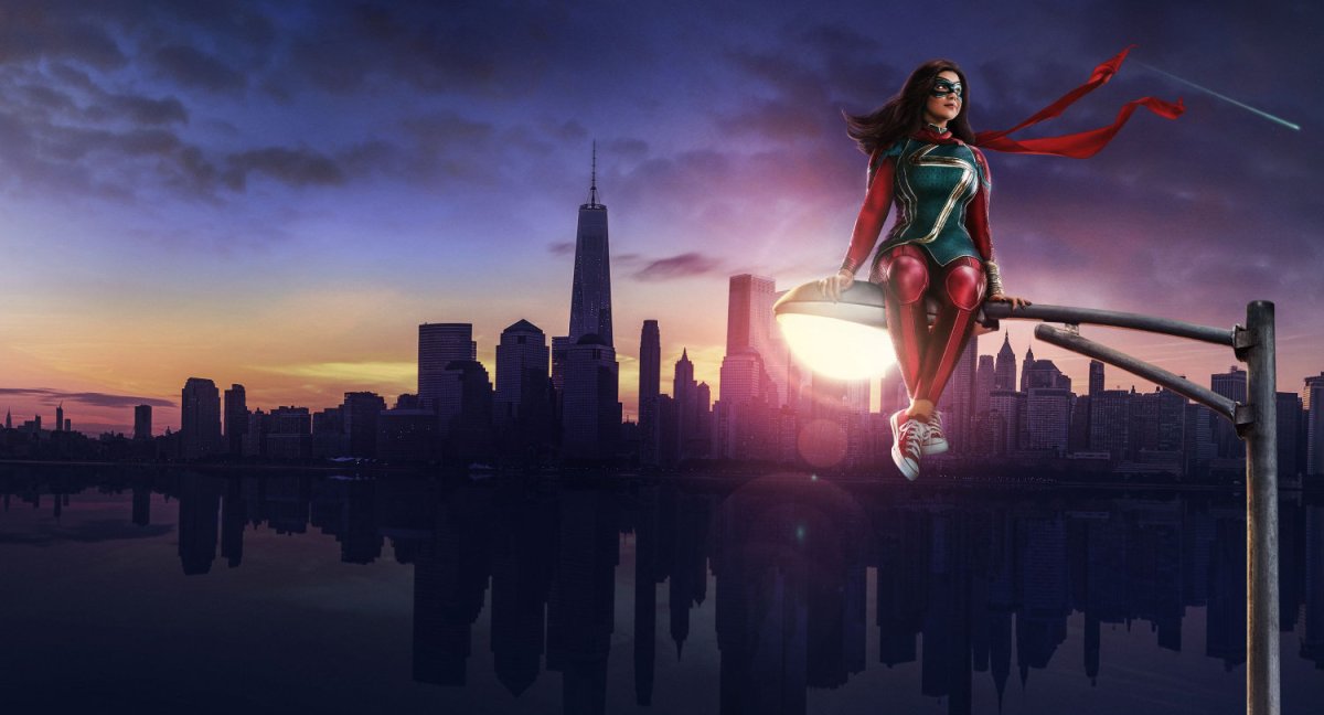 Kamala Khan (Ms Marvel) sits on a streetlight with New York City in the background.
