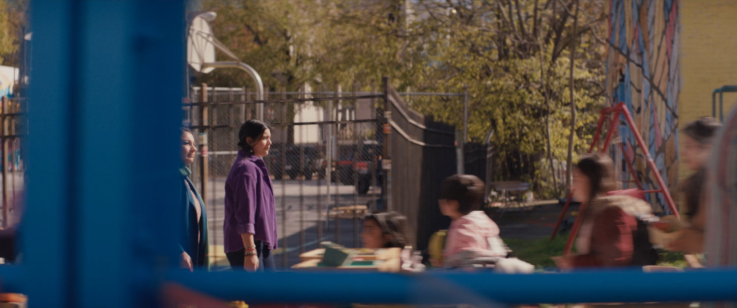 Kamala and Muneeba walk down sidewalk in shopping district.