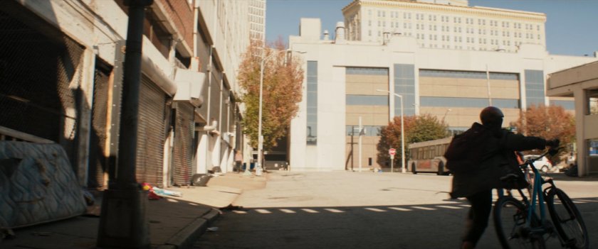 Bruno walking his bike near a city bus.
