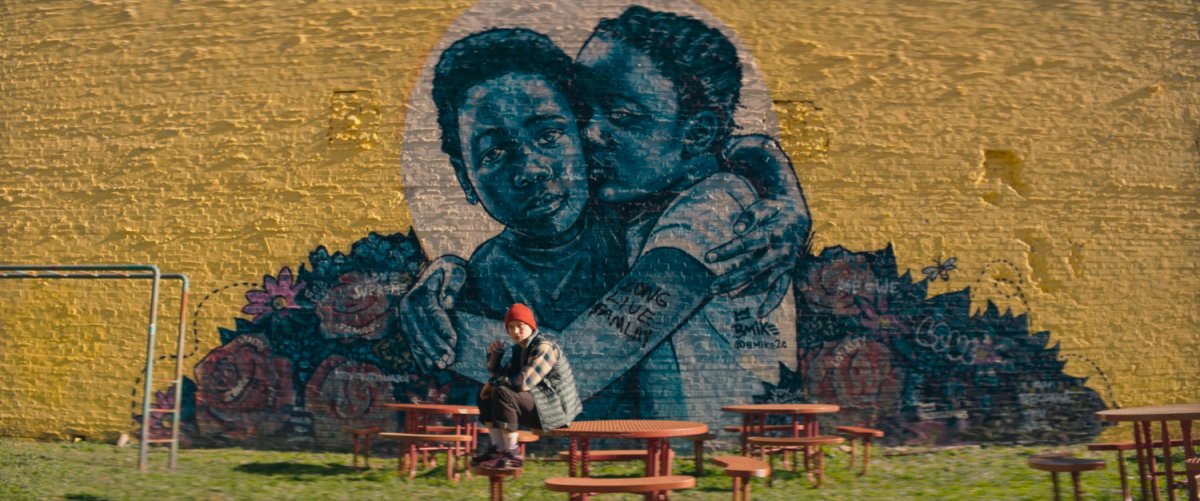 Bruno sitting in front of giant mural on wall at playground.