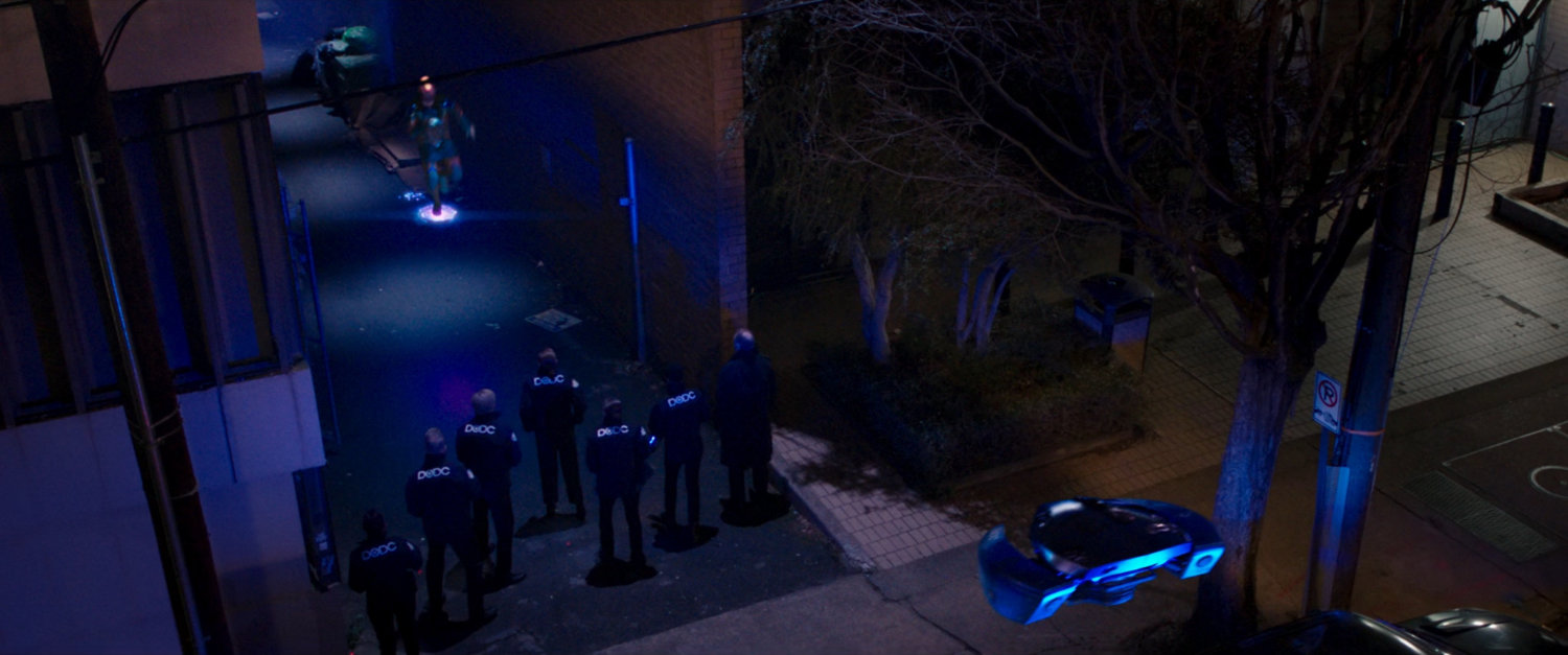 Kamala evade a DODC drone and DODC agents in a dark alley.