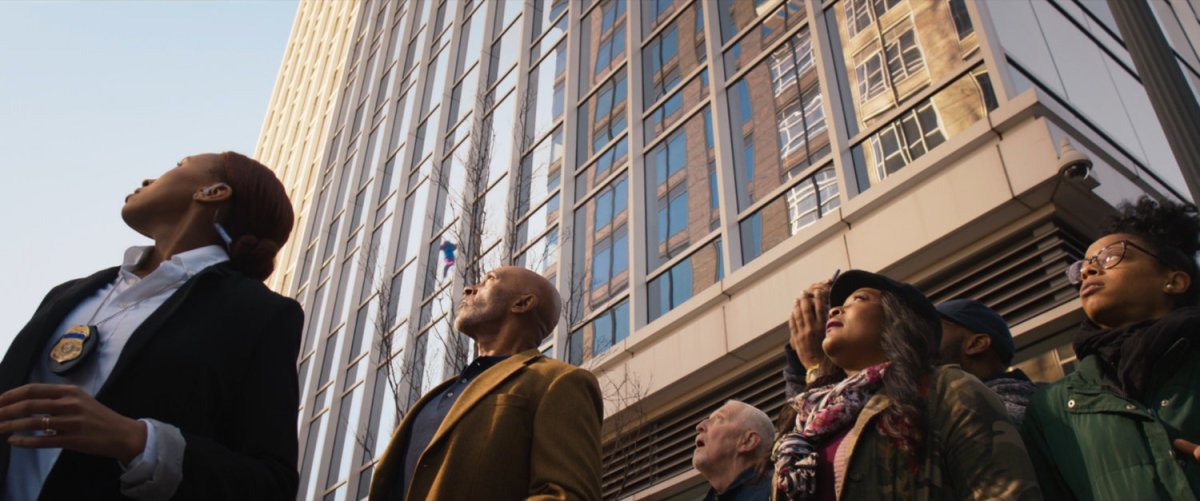 Pedestrians look up in the sky as Ms Marvel runs past on platforms of hard light.