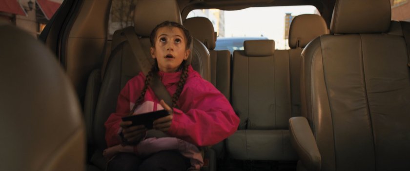 A young girl in car looks up at Ms Marvel.