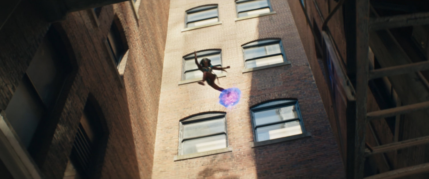 Ms Marvel leaps through an alley on hard light platforms.