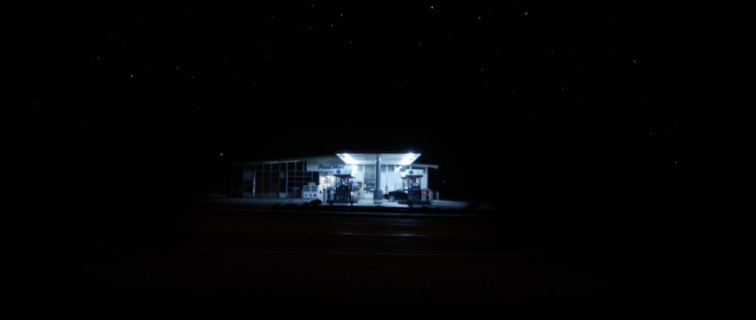 Nighttime shot of illuminated gas station in the darkness.