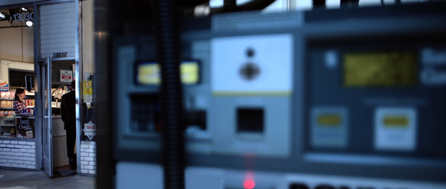 Close up of gas pump with station entrance in background.
