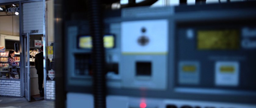 Close up of gas pump with station entrance in background.