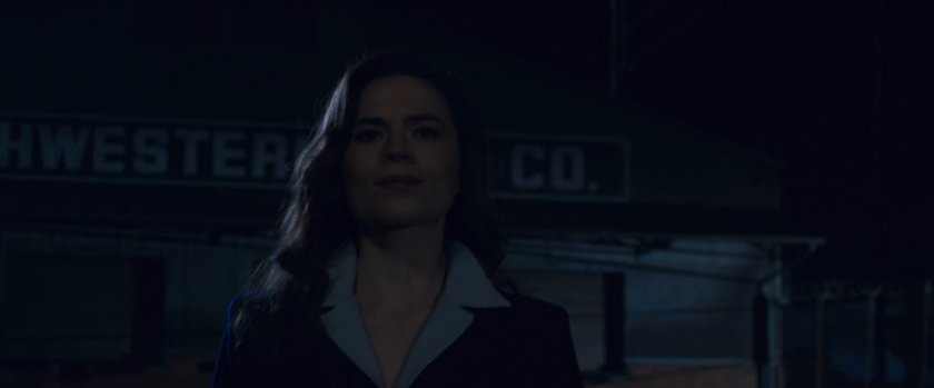 Nighttime shot of Peggy Carter walking towards warehouse.