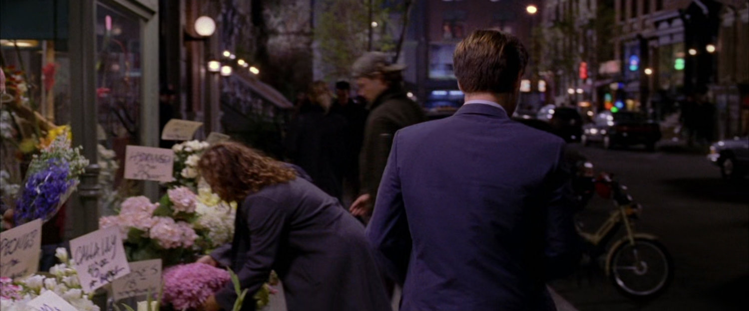Peter Parker walking away from sidewalk flower stand.