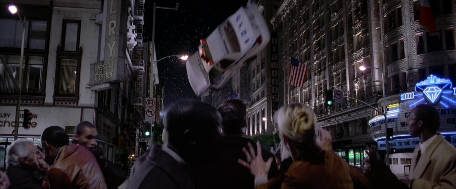NYPD police car flies through air towards onlookers.