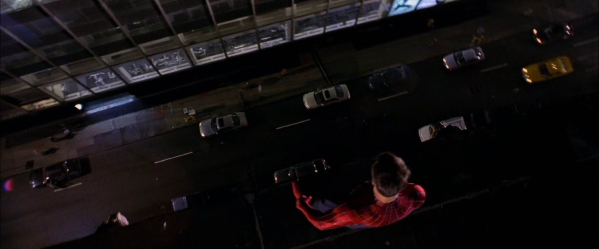 Spider-Man looks down at street from rooftop.