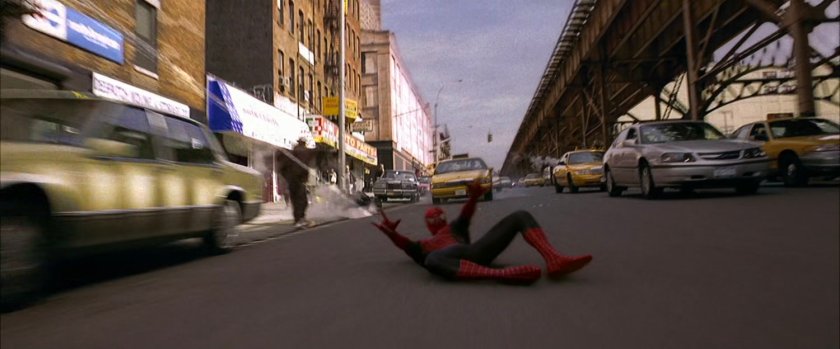 Spider-Man crashes into street next to elevated train tracks.
