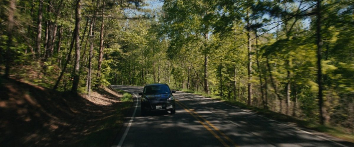 SUV drives on road through California forest