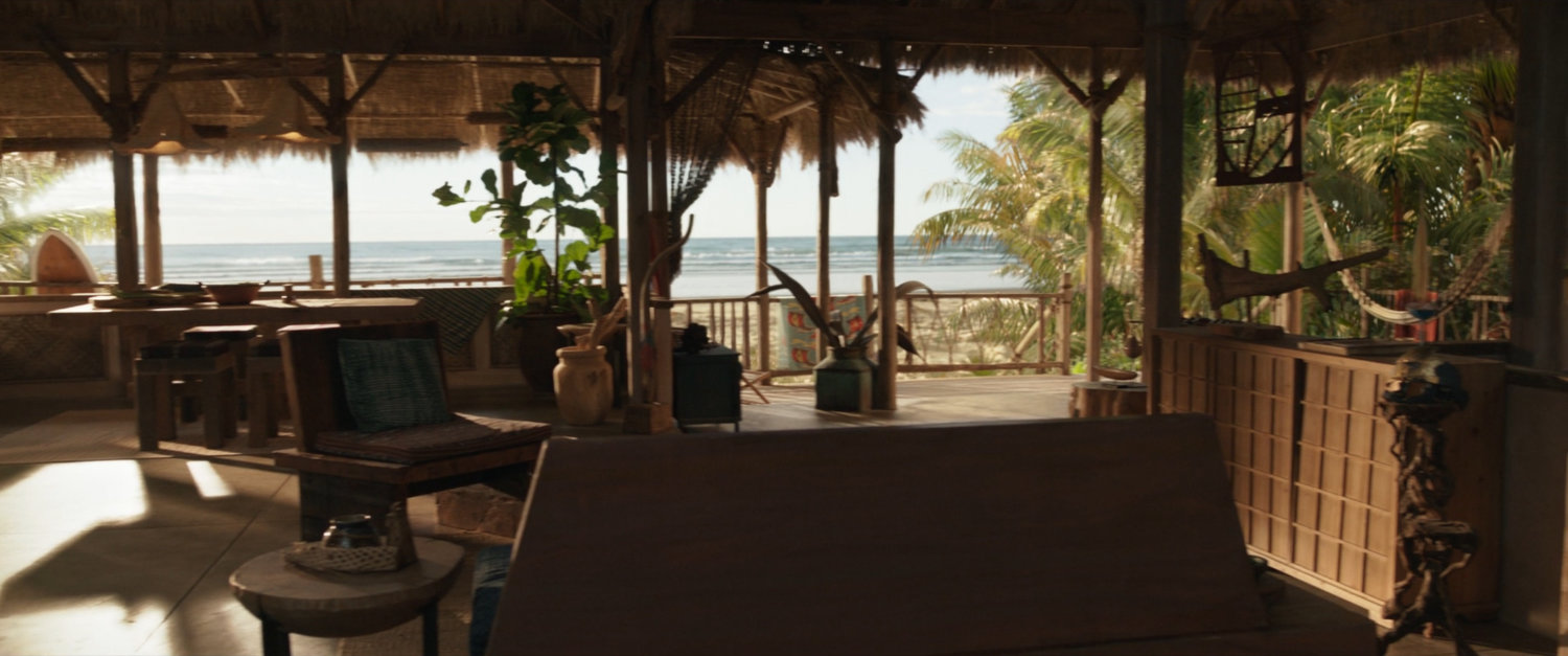 A fancy grass hut with a view of the ocean.