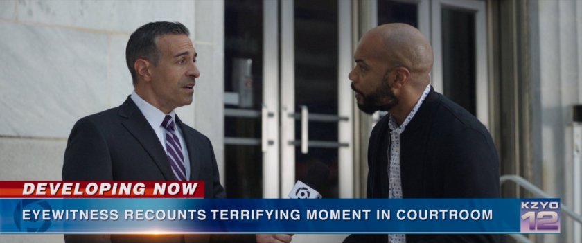 KYZO Reporter talks to an eyewitness in front of courthouse. Text: Developing Now Eyewitness recounts terrifying moment in courtroom.