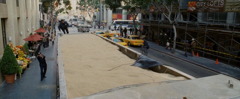 Police officer climbs onto truck filled with sand.