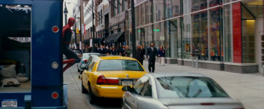 Spider-Man stuck on the side of an armored truck.