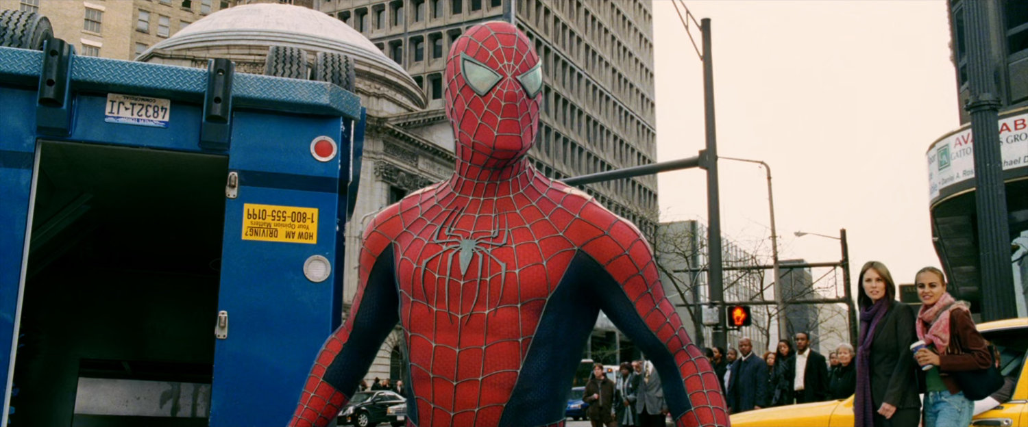 Spider-Man looks off-screen with an upside-down armored truck behind him.