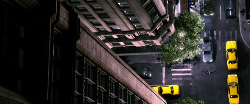 Aerial view of Spider-Man swinging down street.