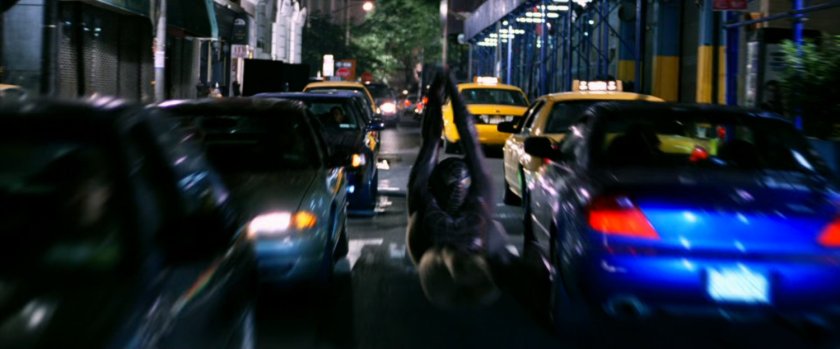 Spider-Man swinging down street.